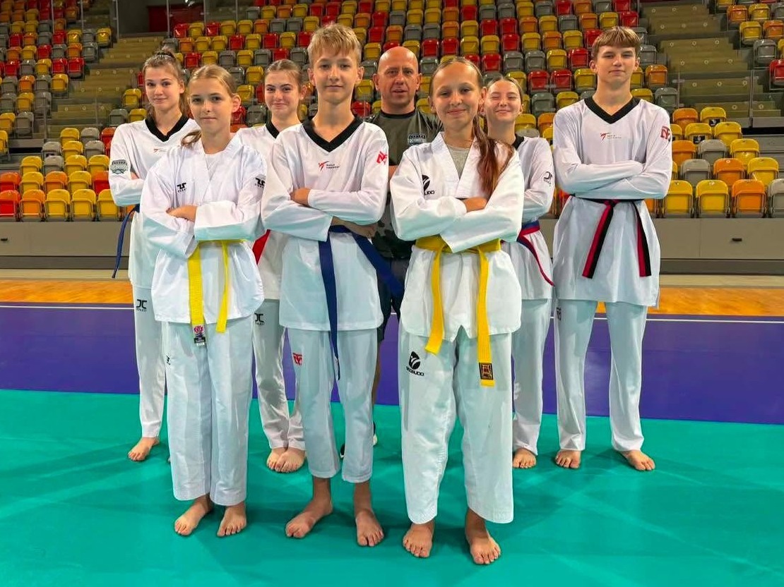 Zawodnicy UKS Żyrzyn Taekwondo Team z trenerem na hali sportowej